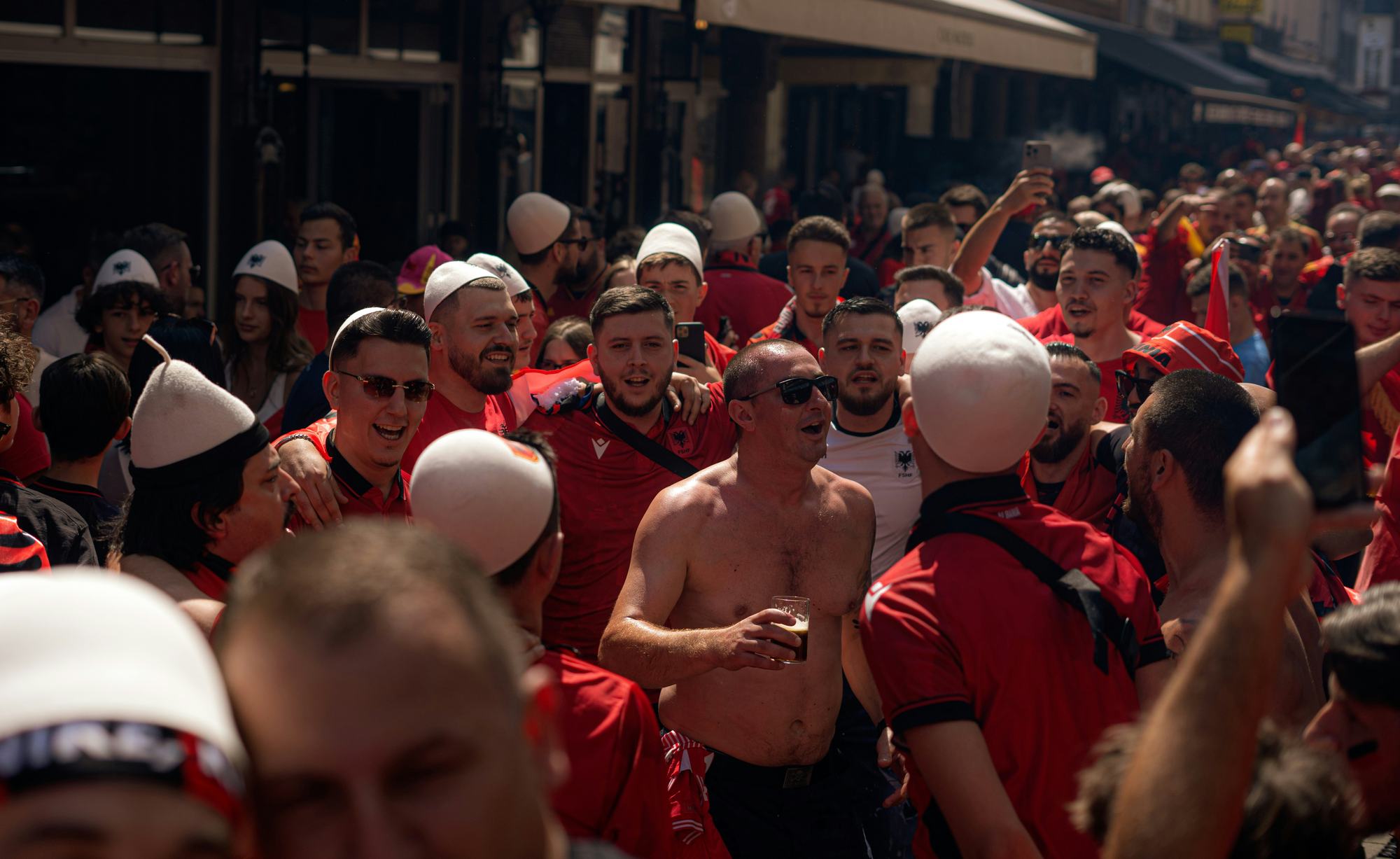 Supporters in red club shirts gathered in a street before a match